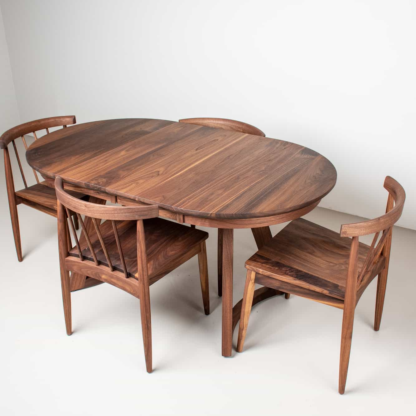 oval extendable dining table with modern walnut chairs