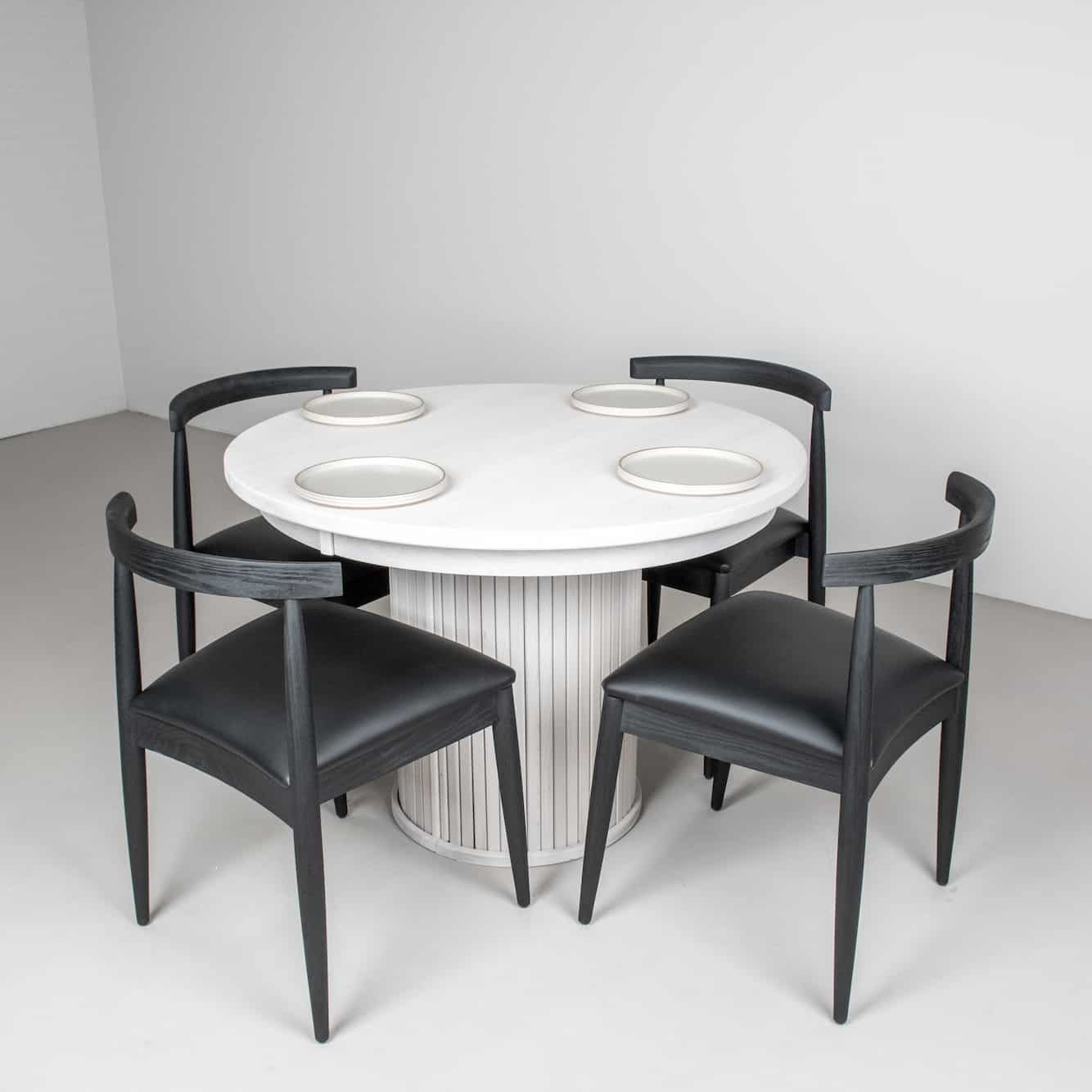 white pedestal table with black chairs